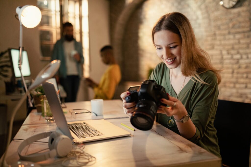 happy-female-photographer-checking-images-digital-camera-while-working-night-studio-1024x683 DFK Consult